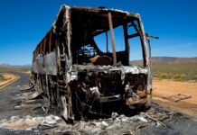 33 Killed, 18 Wounded in Bus Stop Bombing bus crash, burned vehicle, fire damage, crash site, vehicle wreckage, highway accident, desert road
