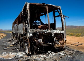33 Killed, 18 Wounded in Bus Stop Bombing bus crash, burned vehicle, fire damage, crash site, vehicle wreckage, highway accident, desert road